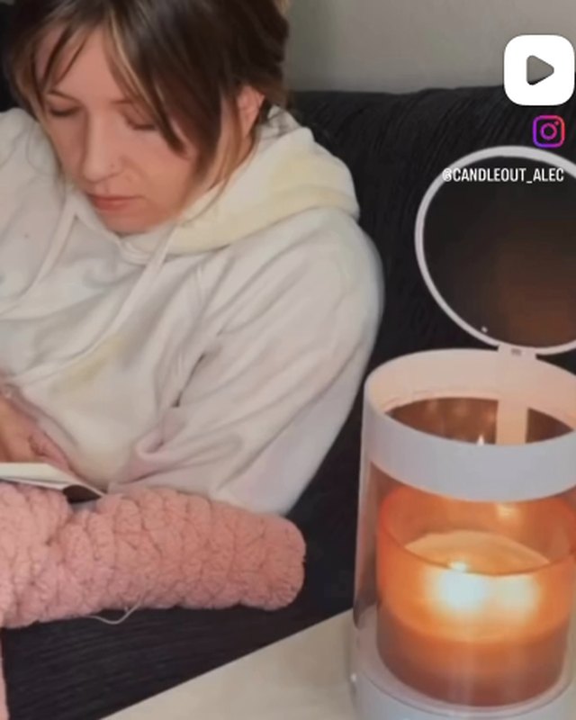 Reading on the couch next to a white ALEC with a lit candle