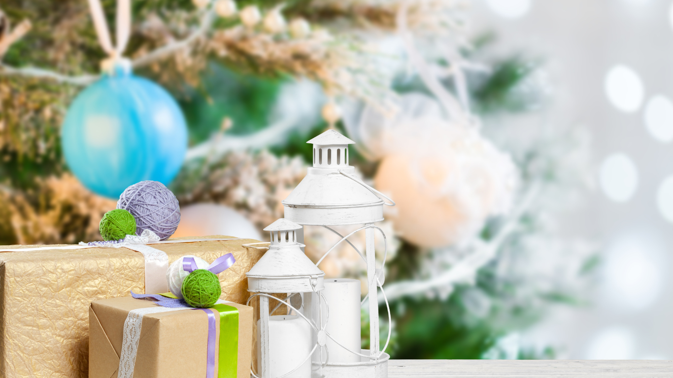 Wrapped gifts and decorative lanterns in front of a Christmas tree with soft, colorful lights.